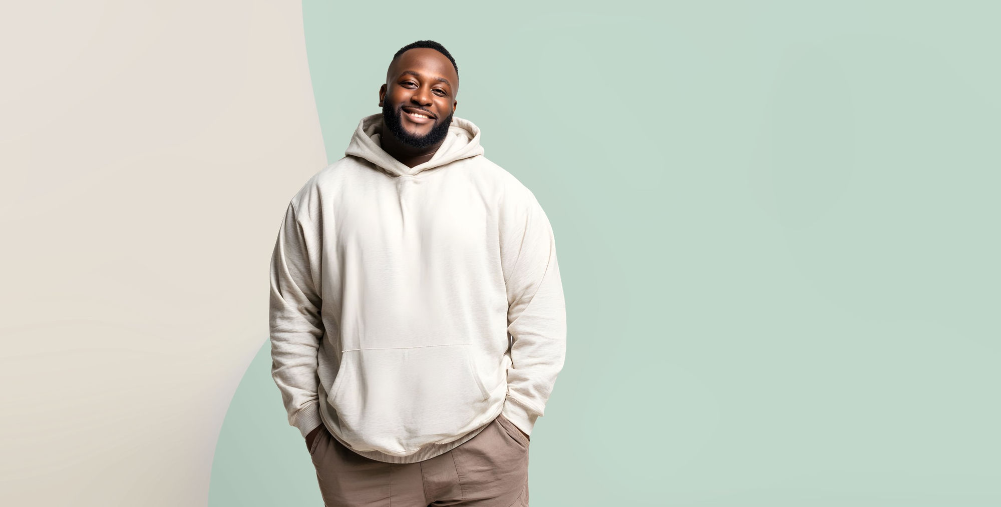 A Healed member smiling, hands in hoodie pockets, against a soft sage and cream background
